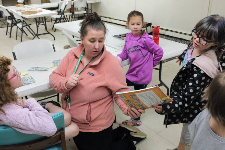Guide Jessica Rothbart, second from left, settles kids into core skills time when they work on math, reading and English at Micah Studios in Newport, N.H., on Monday, April 18, 2024. From left are Chelsea Martin, 9, Rothbart, her daughter Kairi Rothbart, 8, and Izzy Pitts, 8. Three of Rothbart's children attend the “individualized learning” center and her three older children work there as interns. (Valley News - James M. Patterson) Copyright Valley News. May not be reprinted or used online without permission. Send requests to permission@vnews.com.