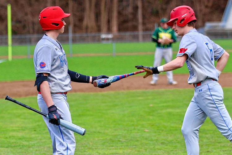 Hartford High's Wyatt Chambers, left, hands Sean Dunton his bat during the Hurricanes' 18-0 defeat of Windsor on April 15, 2024, in Windsor, Vt. (Valley News - Tris Wykes) Copyright Valley News. May not be reprinted or used online without permission. 