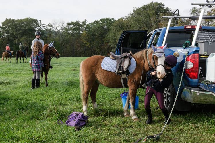 Hayden Harris-Reiss, 10, of South Royalton, right, puts a bridle on pony Elvis before riding with in the High Horses 30th annual benefit trail ride at Pirouette Farm with Heron Harris-Reiss, 12, on Butterscotch, at left, and friend Skyley Hudson, 12, also of South Royalton, in Norwich, Vt., on Saturday, Oct. 14, 2023.(Valley News - James M. Patterson) Copyright Valley News. May not be reprinted or used online without permission. Send requests to permission@vnews.com.