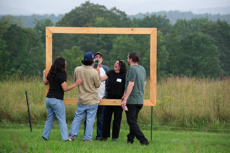 From left, Jenery Contreras, Justin Fitch, and Tim Fitch, of California, laugh with Andie Fitch and Chris Brose, right, of Chicago, over a family photo taken inside a frame of the view over the Fitch farm, in Cornish, N.H., on Saturday, July 29, 2023. Tim Fitch visited the farm on long vacations in his childhood.  (Valley News - James M. Patterson) Copyright Valley News. May not be reprinted or used online without permission. Send requests to permission@vnews.com.
