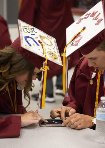 Meagan Thompson, left, and Ean Ray play air hockey on Ray’s phone before their graduation ceremony at Lebanon High School in Lebanon, N.H., on Thursday, June 8, 2023. (Valley News / Report For America - Alex Driehaus) Copyright Valley News. May not be reprinted or used online without permission. Send requests to permission@vnews.com.