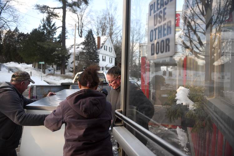 Windsor Diner owner Theresa Taylor, middle, helps Andy Briggs and Kristen Reed move a pastry cooler out of the diner on Tuesday, Feb. 18, 2025, in Windsor, Vt. The cooler is going to Maebelline's, a restaurant in Springfield, Vt. Taylor is hoping to move the diner to another location in Windsor. (Valley News-Jennifer Hauck)