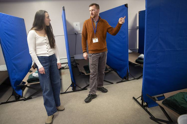 Kyle Deremer, right, seasonal shelter associate, gives Kyra Lee, a first year medical student at Dartmouth, a brief tour of the facility before the start of her first volunteer shift at the emergency winter shelter in Lebanon, N.H., on Thursday, March 20, 2025. The shelter’s 14 beds, up from 12 last year, have been full nearly every night since it opened for the season on January 8. (Valley News - Alex Driehaus)
