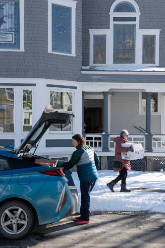 Library Director Kate Minshall, left, helps adult services and technology librarian Nancy Fontaine, right, unload her car while moving office supplies back to the Enfield Public Library at Whitney Hall in Enfield, N.H., from a temporary space at the former LaSalette Shrine following a renovation of the building on Tuesday, Jan. 21, 2025. About 800 boxes filled with supplies and the library's 21,000 items of books, audio and video media need to be moved back in and re-shelved. (Valley News - James M. Patterson) 