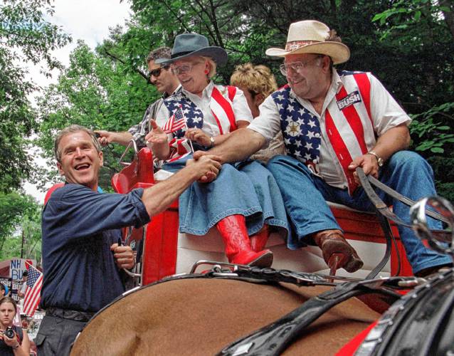 Presidential hopeful George W. Bush greets supporters at the start of a parade in Merrimack, N.H., on July 4, 1999. (AP Photo/Joel Page)