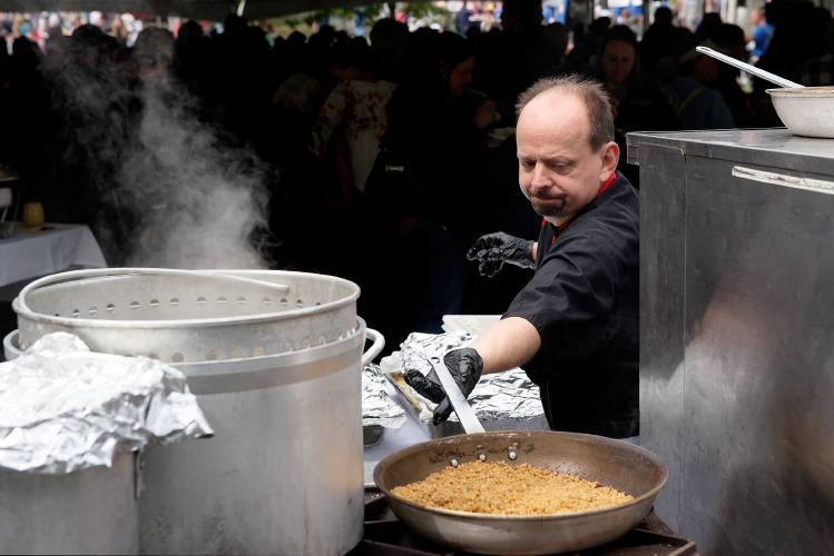 Gene McCray, executive chef of Blood's Catering, reaches out to stir the crumbled topping warming on a burner while preparing macaroni and cheese at the Vermont Mac and Cheese Challenge at Artisan's Park in Windsor, Vt., Sunday, Sept. 9, 2018. McCray prepared 40 gallons of cheese sauce to serve over 3,000 tasters for the contest, following his normal macaroni and cheese recipe with no alterations for the competition.  (Valley News - James M. Patterson) Copyright Valley News. May not be reprinted or used online without permission. Send requests to permission@vnews.com.