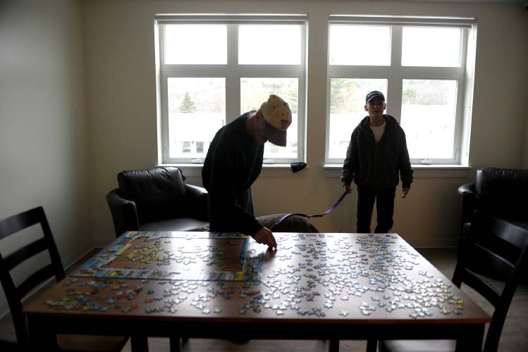 Freddy Bailey tours the common room in his apartment complex on Thursday, Dec. 19, 2024, in White River Junction, Vt. Bailey moved into one of the 18 one-bedroom units after being chronically homeless. Another resident who did not want to give his name was working on a puzzle.  (Valley News-Jennifer Hauck)
