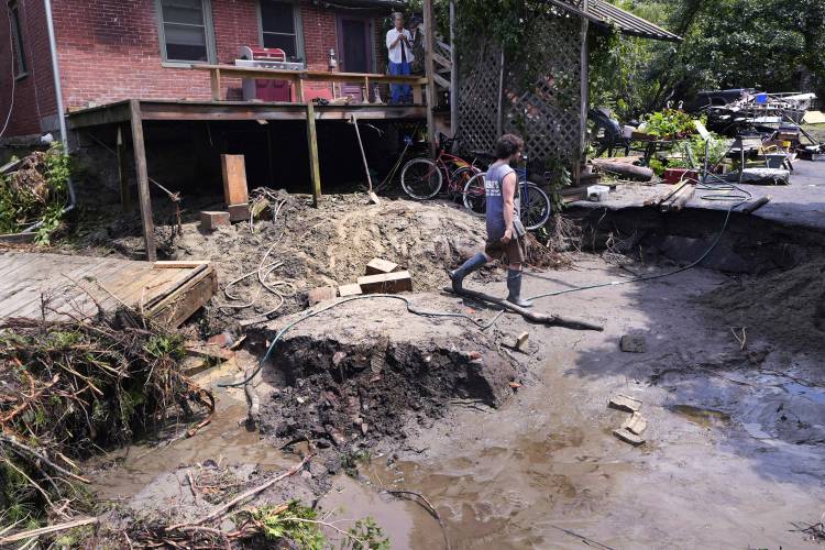 August Thompson walks over the washed out remains of the road in front of his grandfather's home after remnants of Hurricane Beryl caused flooding and destruction, Friday, July 12, 2024, in Plainfield, Vt. (AP Photo/Charles Krupa)