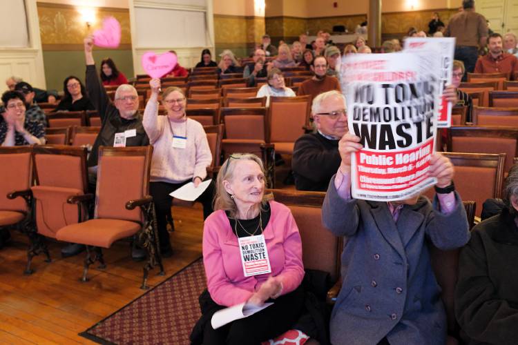 Claremont residents, and members of A Better Claremont, Judith Koester, front center, Cornelia Sargent, front right, Jim Contois, back left, and Rebecca MacKenzie, back right, wave signs and applaud a speaker during a New Hampshire Department of Environmental Services public hearing for a permit modification requested by Acuity at the Claremont, N.H., Opera House on March 6, 2025, for Acuity Management. If approved, Acuity would begin accepting construction and demolition waste to be sorted at its recycling facility in the city. (Valley News - James M. Patterson) Copyright Valley News. May not be reprinted or used online without permission. Send requests to permission@vnews.com.