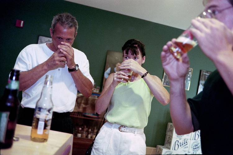 Terry Landis, left, of Boyertown, Pa., and Mary McCann, of Lansdale, Pa., taste Catamount's new Northern Brite at the company's Windsor, Vt., brewery on July 2, 1999. At right is Catamount's Jeff Close, who is showing the tourists the fine points of proper beer tasting. (Valley News - Amy Thompson)