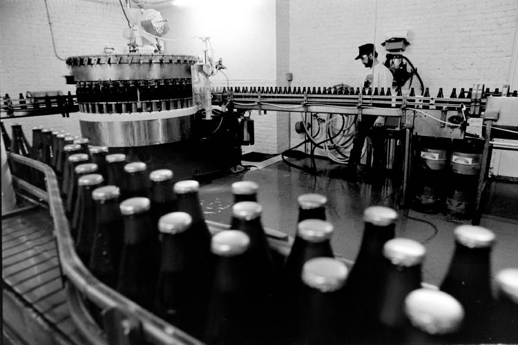 Catamount production manager Ron Schmidt hoses off the floor on the White River Junction, Vt., brewery on March 29, 1991, while bottles are filled and capped. (Valley News - Geoff Hansen)