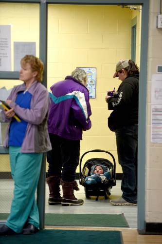 Before heading into Lyme’s Town meeting, Martha Smith, left, and Taylor Gray wait with Gray's child Colton Smith, eight months, on Tuesday, March 11, 2025, in Lyme, N.H. Smith is the baby's grandmother. At left is community nurse Melissa Ball. (Valley News-Jennifer Hauck)