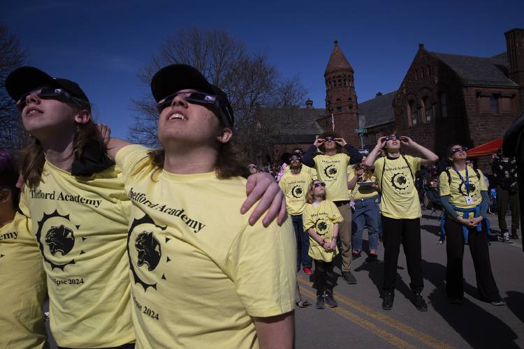 Thetford Academy students Shawn Thomas, left, and AJ Foster, second from left, both 15, watch the solar eclipse outside of the Fairbanks Museum and Planetarium in St. Johnsbury, Vt., on Monday, April 8, 2024. The trip up to the path of totality from Thetford was organized by Scott Ellis, outdoor program coordinator, third from right, who brought along almost 40 students and chaperones and his daughter Maggie Ellis, 9, center. “It’s the coolest thing I’ve ever seen,” Maggie said of the total solar eclipse. (Valley News / Report For America - Alex Driehaus) Copyright Valley News. May not be reprinted or used online without permission. Send requests to permission@vnews.com.