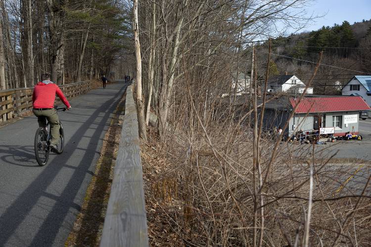 A cyclist rides along the Mascoma River Greenway, which passes behind the emergency winter shelter in Lebanon, N.H., on Wednesday, March 19, 2025. The seasonal shelter is open every night from 5 p.m. to 8 a.m. until mid-April and offers guests dinner and to-go breakfast, along with access to showers and a place to store belongings during the day. (Valley News - Alex Driehaus)
