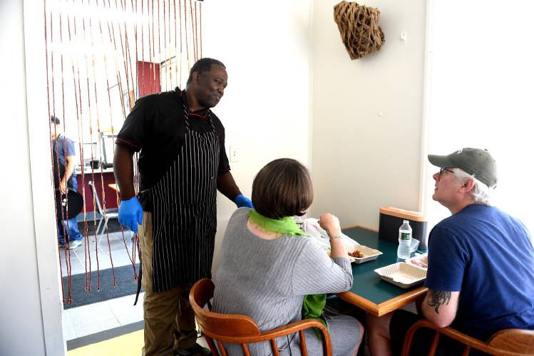 Cheryl Junker and husband Josh Macomson, of Canaan, N.H., sit down for their first meal at The Karibbean on Friday, July 26, 2024, in West Lebanon, N.H. Owner Balvin Bowen checks on the couple after they are served. The couple said they were very excited to have good Jamaican food in the area. (Valley News - Jennifer Hauck) Copyright Valley News. May not be reprinted or used online without permission. Send requests to permission@vnews.com.