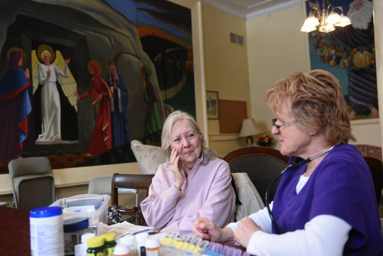 Geri Burgess, of Lyme, N.H., laughs with parish nurse Missy Ball during a visit on Tuesday, March 25, 2025, at the Lyme Congressional Church. Ball helps Burgess organize her medications about once a week. Spending about an hour together, they chat, look at old photos Burgess carries with her and discuss her upcoming medical appointments. (Valley News-Jennifer Hauck)