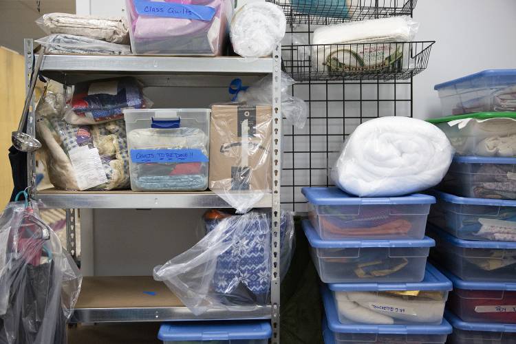 Customer quilts, both in progress and ready for pickup, are stored in totes and plastic bags to protect them from demolition debris at Golden Anchor Quilting in Claremont, N.H., on Wednesday, March 12, 2025. “We’re more of a mental health resource than a fabric retailer,” co-owner Louisa Grindle said, noting that people come to the shop to socialize and take their minds off of daily difficulties while working on their quilts. (Valley News - Alex Driehaus)
