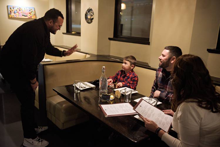 Ernesto Medina, left, talks with Malyn Gomez, 5, after getting him a toy car to play with at the table with his dad Jaime, and mom Ziang, right, at Little Havana in Hanover, N.H., on Saturday, Dec. 3, 2024. The Gomez family traveled from Bellows Falls to sample the food at the Cuban restaurant. (Valley News - James M. Patterson) 