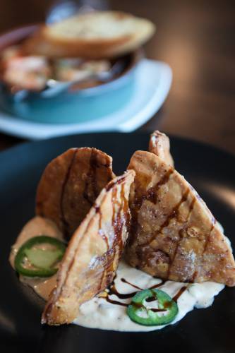 Chicken tinga empanadas, foreground, and gambas y chorizo, background are on the menu of Casa Brava Tapas Lounge at Six South Street Hotel in Hanover, N.H., on Saturday, Dec. 14, 2024.(Valley News - James M. Patterson) 