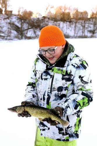 Jackson Burch, 13, of Windsor, Vt., shows off a chain pickerel he caught with his sister during an ice fishing derby on Lake Runnemede in Windsor, Vt., on Jan. 20, 2025. The event was part of Windsor High senior Cole Anderson's capstone project. (Valley News - Geoff Hansen)