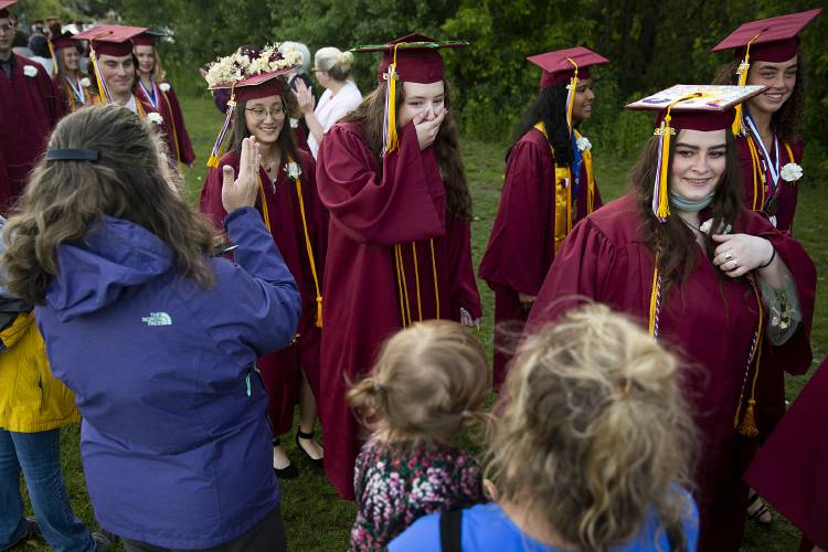 Katherine Clancy, center, reacts to seeing her first grade teacher Lindsay McKittrick, holding her daughter Adelaide, 2, before graduation at Lebanon High School in Lebanon, N.H., on Thursday, June 8, 2023. Graduates in the class of 2023 were students in McKittrick’s first ever class when she started teaching and she said attending their graduation was a special moment for her. (Valley News / Report For America - Alex Driehaus) Copyright Valley News. May not be reprinted or used online without permission. Send requests to permission@vnews.com.