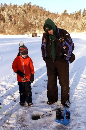 Bill Gokey, Jr., of Weathersfield, Vt., helps Elliot Bevis, 7, of Windsor, Vt., lure in a fish with an electronic finder during an ice fishing derby on Lake Runnemede in Windsor, Vt., on Jan. 20, 2025. Gokey is a member of the Windsor Coon Club and an assistant with the Windsor Recreation Department, hosts of the event organized by Windsor High senior Cole Anderson as part of his capstone project. (Valley News - Geoff Hansen)