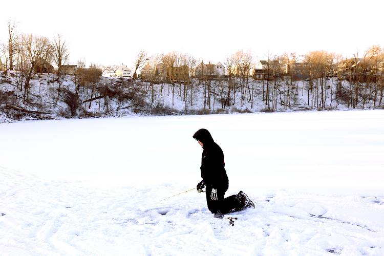 Wes Merriam, 14, of Claremont, N.H., uses a rod and reel in an ice fishing hole during a derby on Lake Runnemede in Windsor, Vt., on Jan. 20, 2025. Moments later he caught a small perch that he released back into the lake. (Valley News - Geoff Hansen)